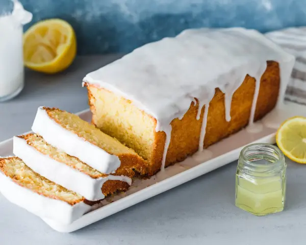 Saftiger Zitronenkuchen mit Zuckerguss, perfekt für ein einfaches zitronenkuchen rezept. Serviert mit frischen Zitronenscheiben.