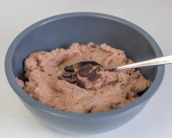 Schokosahne rezept: cremige Schokoladencreme in einer Schüssel, garniert mit Schokodrops und einem Löffel.