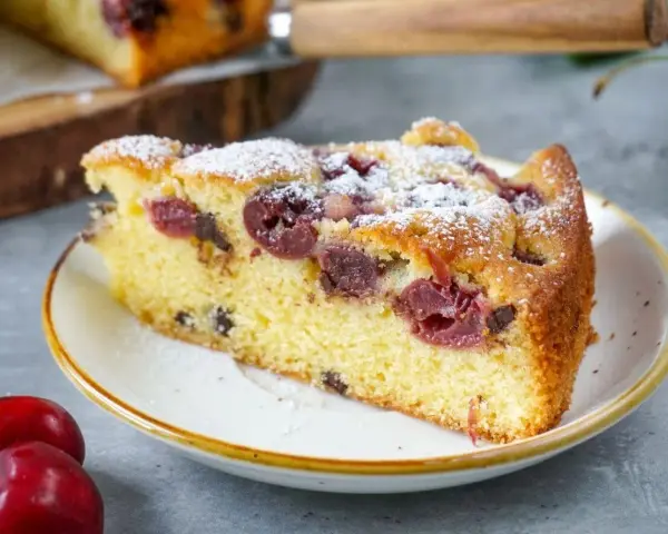Ein saftiges Stück Kirschkuchen, bestäubt mit Puderzucker. Dieses Kirschkuchen Rezept ist ein Genuss!