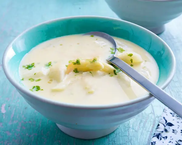 Cremige Spargelsuppe mit Petersilie in einer blauen Schüssel. Perfekt zum Spargelsuppe einfrieren für später.