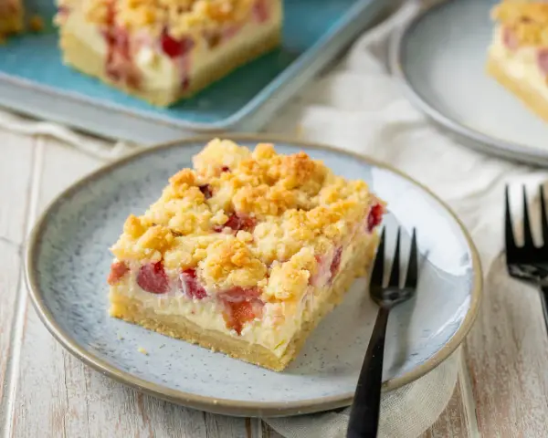 Ein Stück von Omas Rhabarberkuchen mit Quark und Streuseln auf einem Teller, bereit zum Genießen.