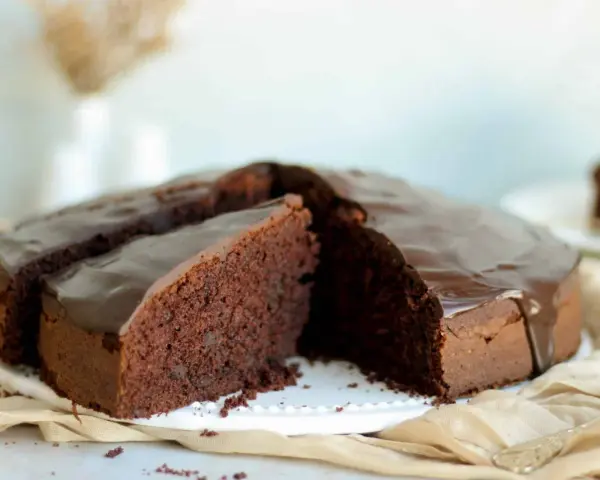 Ein saftiger Schokokuchen mit glänzender Glasur, perfekt für jedes schokokuchen rezept. Ein Stück ist bereits angeschnitten.