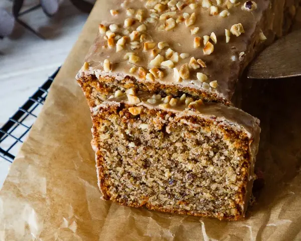 Saftiger Nusskuchen mit Zuckerguss und gehackten Nüssen, perfekt für ein gemütliches Kaffeetrinken. Ein tolles Nusskuchen Rezept!