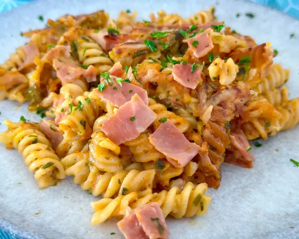 Nudel Schinken Gratin mit Käse überbacken, garniert mit Petersilie. Ein herzhaftes Gericht, das zum Genießen einlädt.