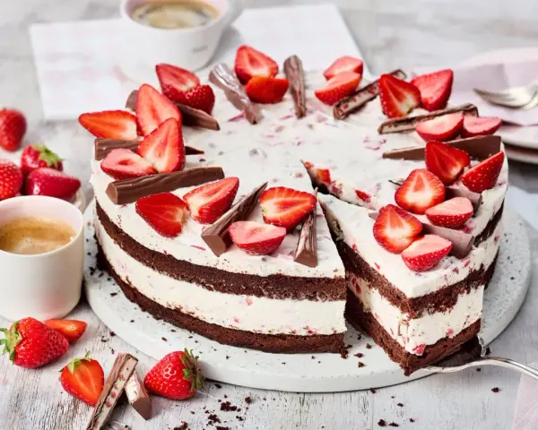 Eine köstliche Yogurette Torte mit frischen Erdbeeren und Schokostückchen, serviert mit einer Tasse Kaffee.