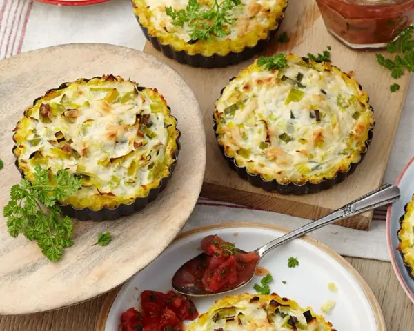Kleine herzhafte Lauch-Tartelettes mit cremigem Belag, garniert mit Petersilie. Perfekt für Lauch Rezepte.