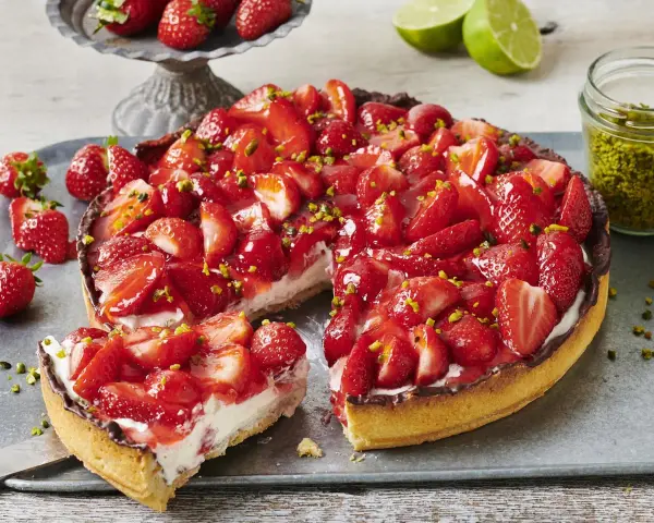 Saftiger Erdbeerkuchen mit frischen Erdbeeren, Sahne und gehackten Pistazien. Ein Traum für alle, die Rezepte mit Erdbeeren lieben!