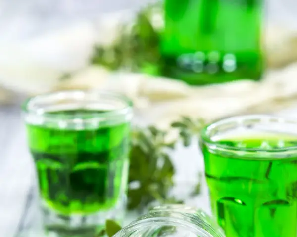 Grüne Gläser mit Waldmeistersirup, perfekt zum Waldmeistersirup selber machen. Frische Kräuter und ein Hauch von Frühling.
