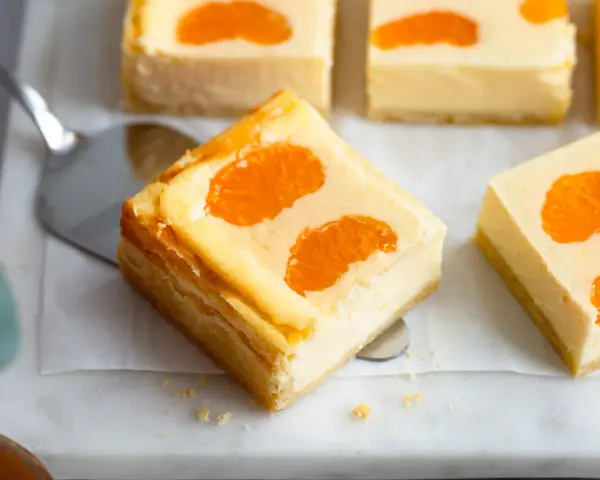 Saftige Stücke von faule weiber kuchen mit Mandarinen auf einem Marmorsockel.