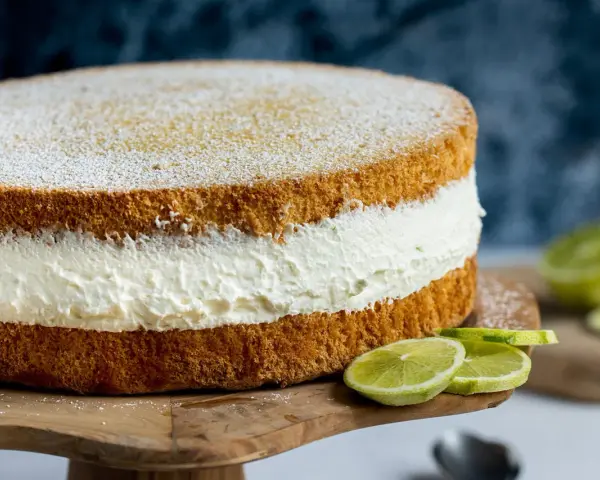 Saftige Quark Sahne Torte mit frischen Limettenspalten, bestäubt mit Puderzucker.