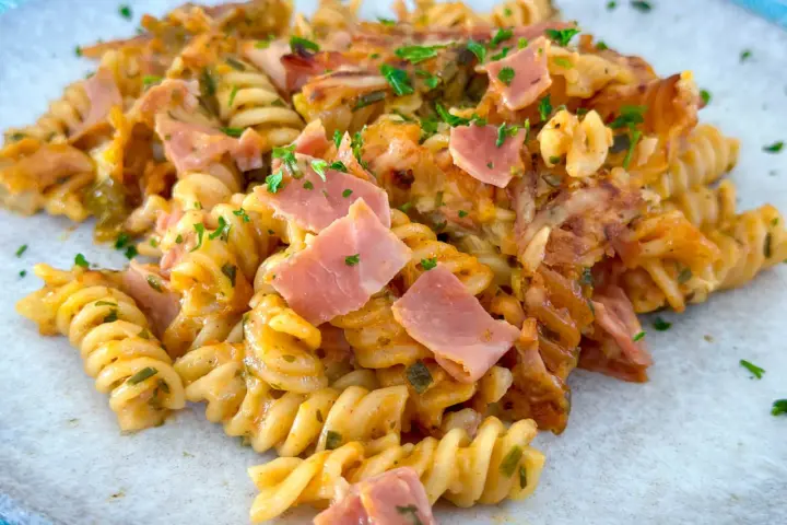 Nudel Schinken Gratin mit Käse überbacken, garniert mit Petersilie. Ein herzhaftes Gericht, das zum Genießen einlädt.