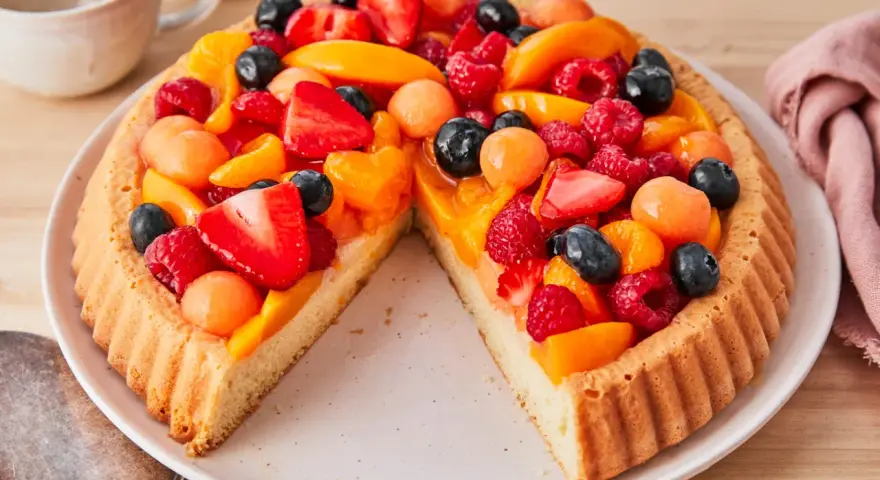 Ein leckerer Obstboden belegt mit Erdbeeren, Himbeeren, Blaubeeren, Aprikosen und Melonenbällchen.