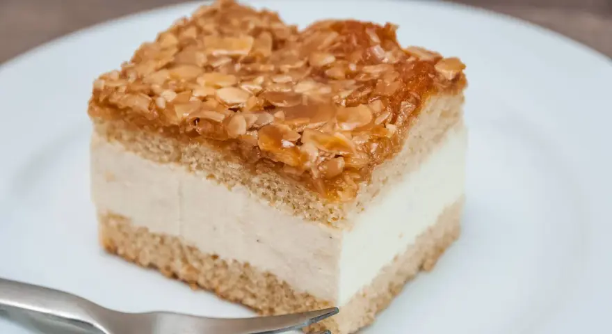 Ein Stück Bienenstich-Kuchen mit cremiger Füllung und karamellisierten Mandeln. Perfekt für das Bienenstich Rezept!