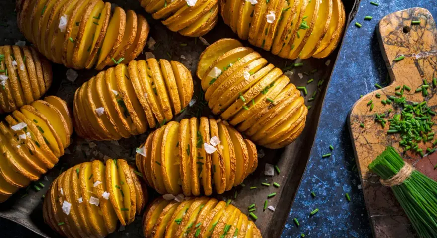 Fertig gegrillte Hasselback-Kartoffeln mit Schnittlauch und grobem Salz, bereit für den Gasgrill.