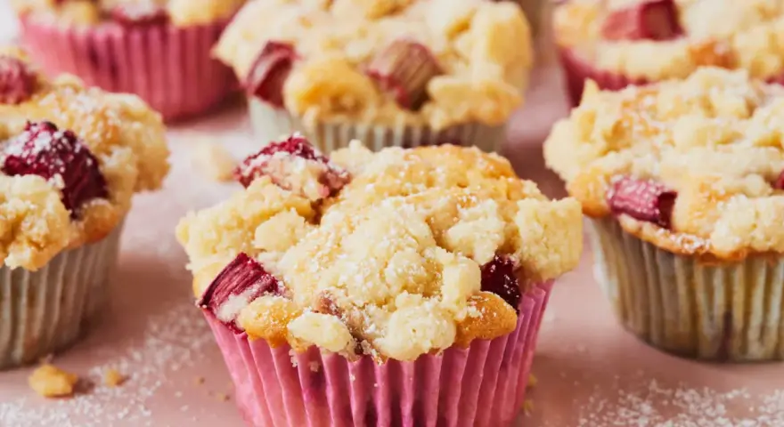 Saftige Rhabarber Muffins mit Streuseln, bestäubt mit Puderzucker. Ein Genuss für jeden Kaffeetisch.