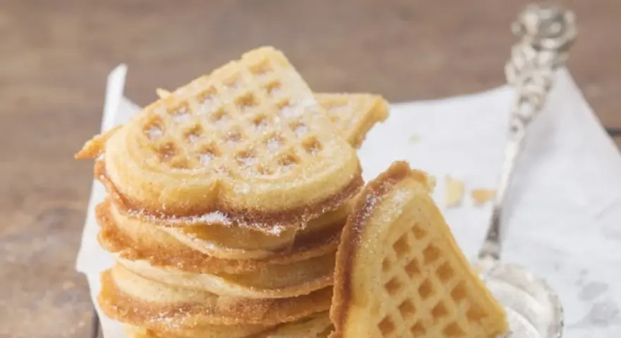 Herzförmige Waffeln, bestäubt mit Puderzucker. Ein perfektes Rezept für süße Momente.