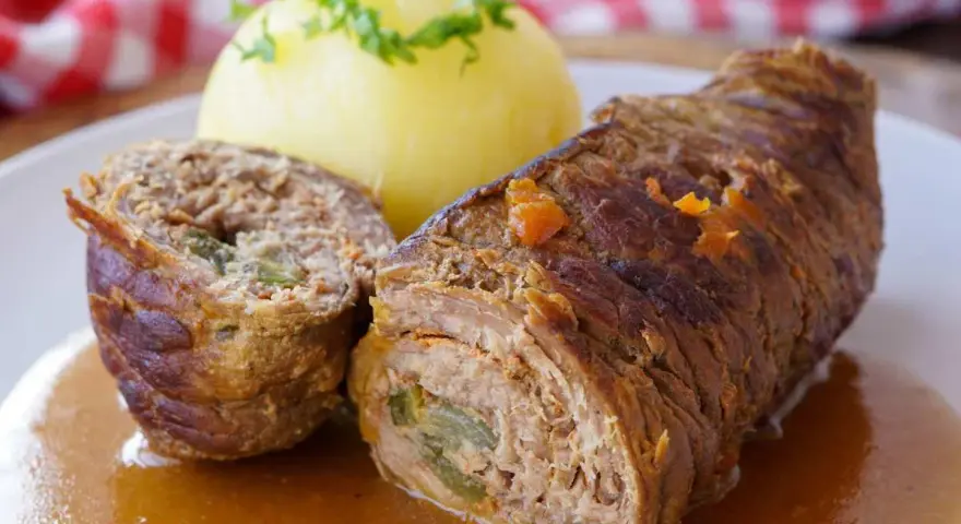 Herzhaftes Rouladen Rezept: Zarte Rinderrouladen mit Kartoffelklößen in einer kräftigen Soße, garniert mit Petersilie.