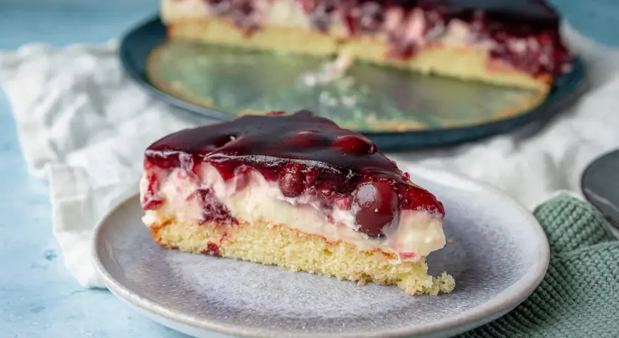 Ein saftiges Stück Kirsch-Sahne-Torte auf einem Teller, perfekt für ein schnelles obstkuchen rezept in der springform.