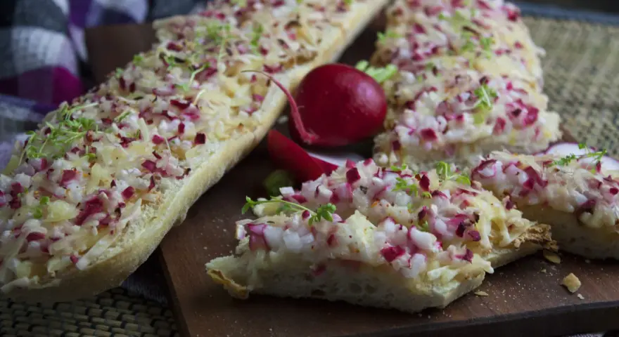 Baguette-Scheiben mit Radieschen und Käse belegt, eine köstliche Idee für Radieschen Rezepte. Frische Kresse garniert die Snacks.