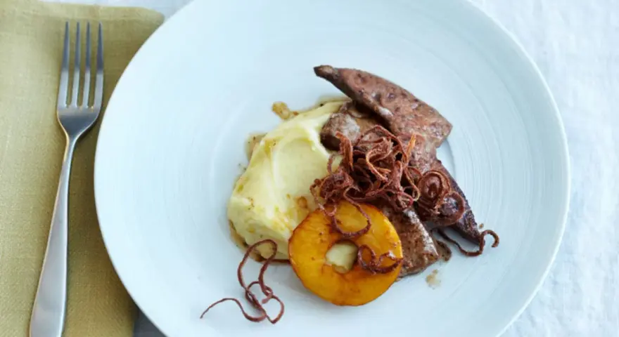 Kalbsleber rezept: Gebratene Kalbsleber mit Kartoffelpüree, Apfelring und knusprigen Zwiebeln auf einem weißen Teller.