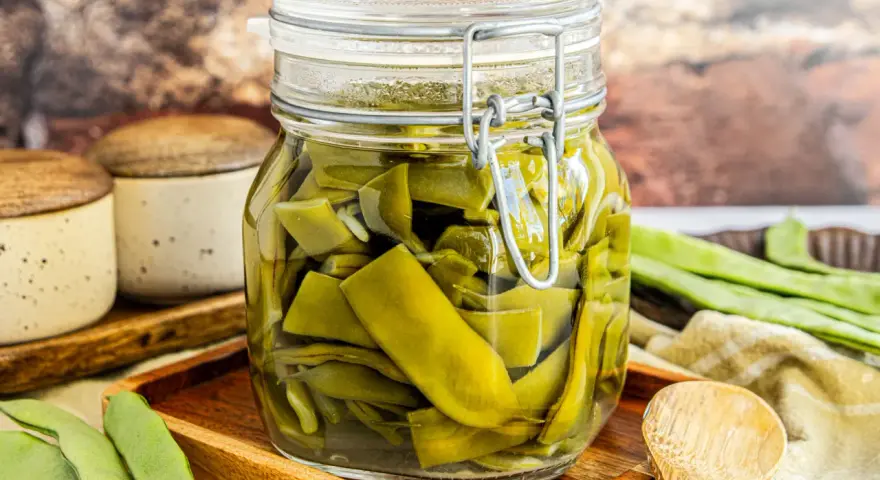 Saure Bohnen im Glas, bereit zum Einlegen. Frische grüne Bohnen, in Stücke geschnitten, schwimmen in einer klaren Flüssigkeit.
