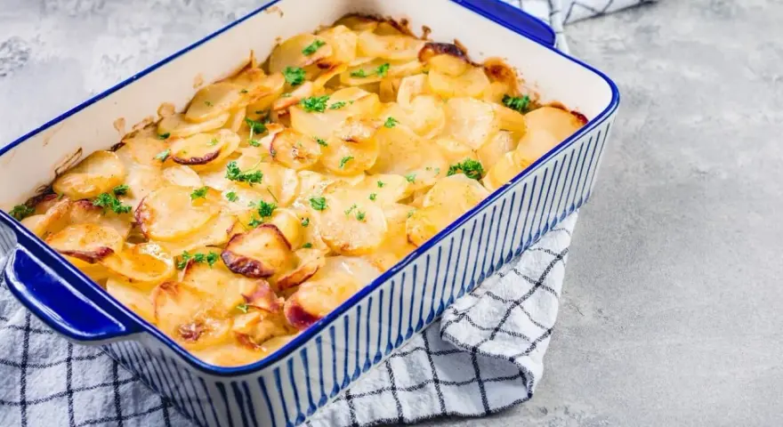 Ein goldbrauner Kartoffelauflauf, garniert mit Petersilie, bereit zum Servieren. Ein köstliches Kartoffelauflauf Rezept.
