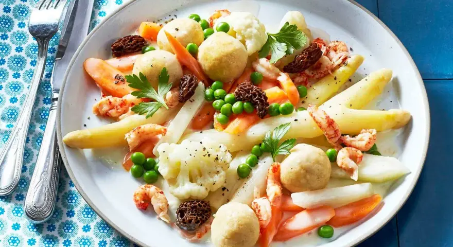 Leipziger Allerlei: Spargel, Erbsen, Karotten, Blumenkohl, Garnelen und Morcheln auf einem Teller.