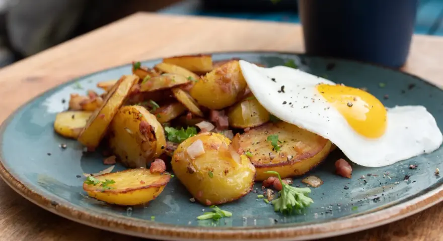 Bratkartoffeln mit Speck und einem Spiegelei, ein klassisches Rezept für ein herzhaftes Frühstück oder Abendessen.