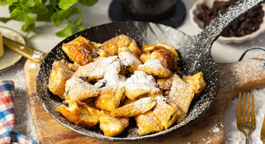 Ein fluffiger Kaiserschmarrn im Pfännchen, bestäubt mit Puderzucker. Perfekt für ein süßes Frühstück oder Dessert.