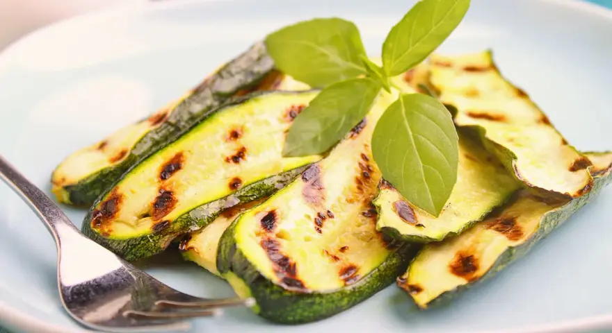 Gegrillte Zucchinischeiben mit Grillstreifen, garniert mit frischem Basilikum. Perfekt für die Sommerküche, diese Zucchini grillen marinade ist ein Genuss.