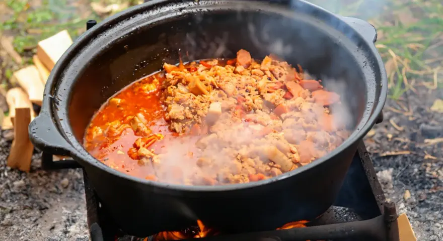 Ein dampfender Kessel mit herzhaftem Kesselgulasch, zubereitet über offenem Feuer. Das perfekte Rezept für ein rustikales Outdoor-Erlebnis.
