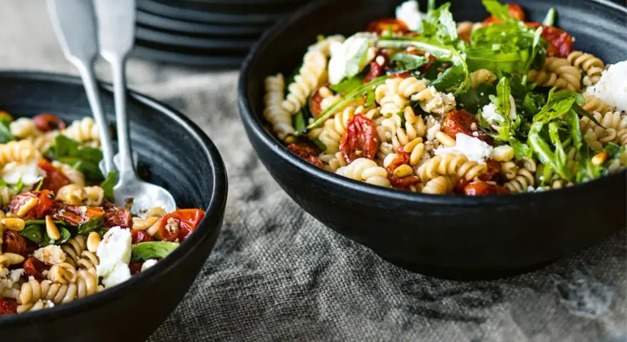 Leckerer Nudelsalat mit getrockneten Tomaten, Pinienkernen und Rucola. Ein einfaches nudelsalat rezept für den Sommer.