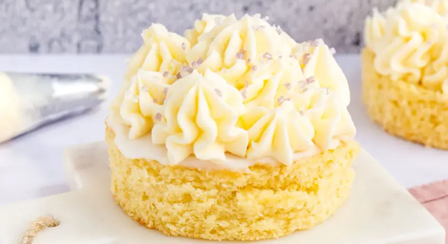 Ein kleiner Kuchen mit omas buttercreme ohne pudding, verziert mit lila Zuckerstreuseln.
