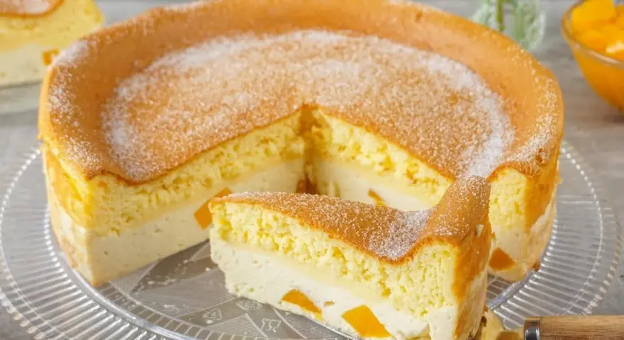 Luftige Eierschecke ohne Boden, mit einer cremigen Füllung und saftigen Fruchtstücken, bestäubt mit Puderzucker.