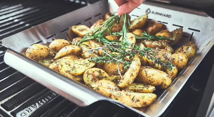 Kartoffeln mit Rosmarin und Thymian in einer Grillpfanne. Perfekt für die Drillinge Kochzeit auf dem Grill.