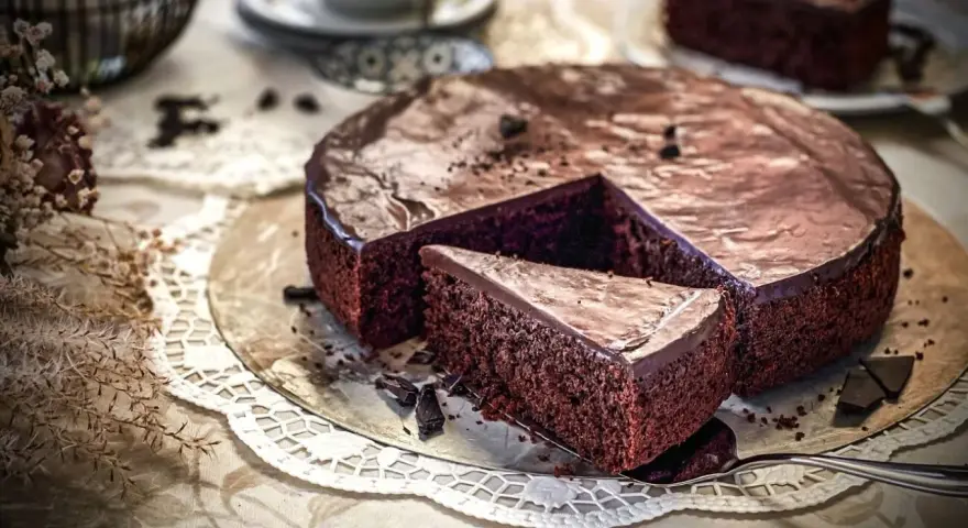 Ein saftiger Schokoladenkuchen mit glänzender Glasur, ein Stück wurde herausgeschnitten. Der einfache Kuchenteig sieht köstlich aus.