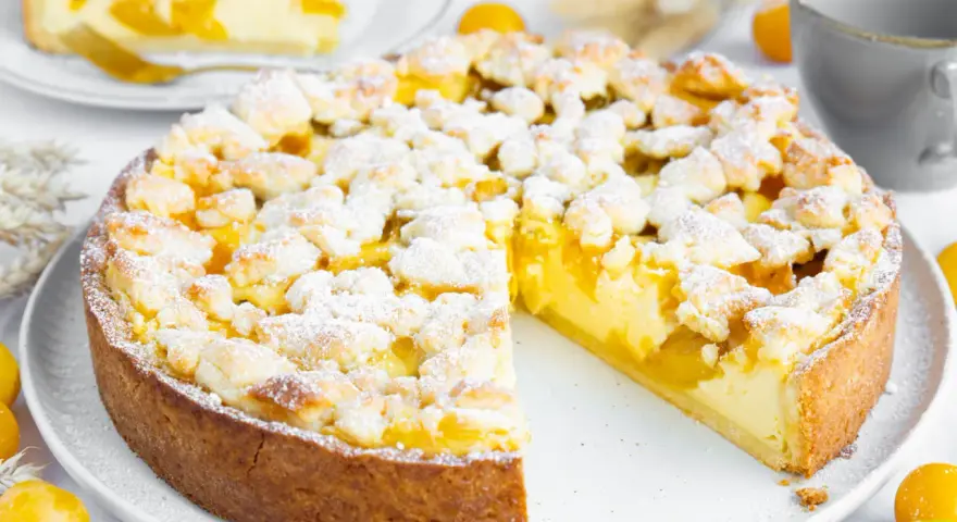 Ein saftiger Mirabellenkuchen mit Streuseln, wie ihn Landfrauen backen. Ein Stück ist bereits angeschnitten.