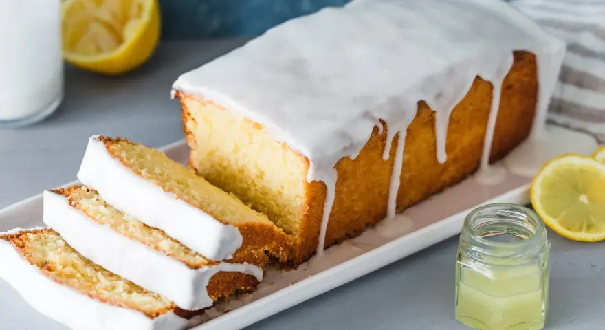 Saftiger Zitronenkuchen mit Zuckerguss, perfekt für ein einfaches zitronenkuchen rezept. Serviert mit frischen Zitronenscheiben.