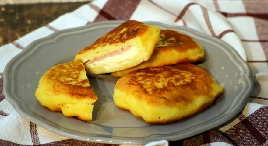 Goldbraune Kartoffel-Cordon-Bleu-Patties auf einem grauen Teller, gefüllt mit Schinken und Käse.