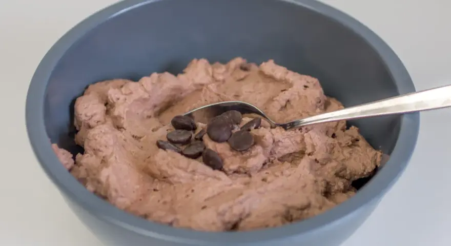 Schokosahne rezept: cremige Schokoladencreme in einer Schüssel, garniert mit Schokodrops und einem Löffel.