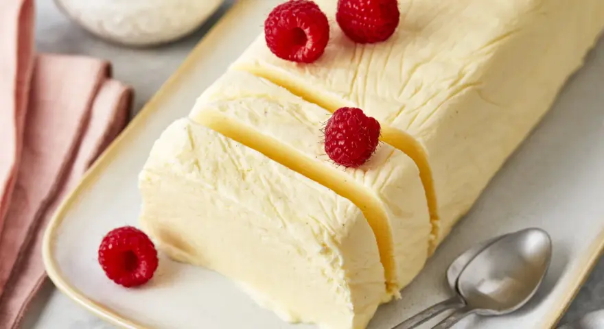 Cremiger Rhabarber Pudding, dekoriert mit frischen Himbeeren, auf einem Teller mit Löffeln.
