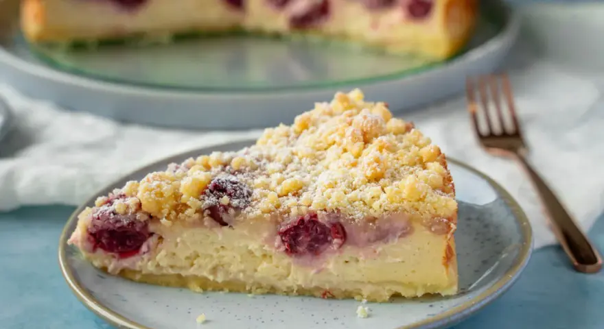Ein Stück saftiger, schneller Quark Kirsch-Kuchen mit Streuseln und Puderzucker bestäubt.