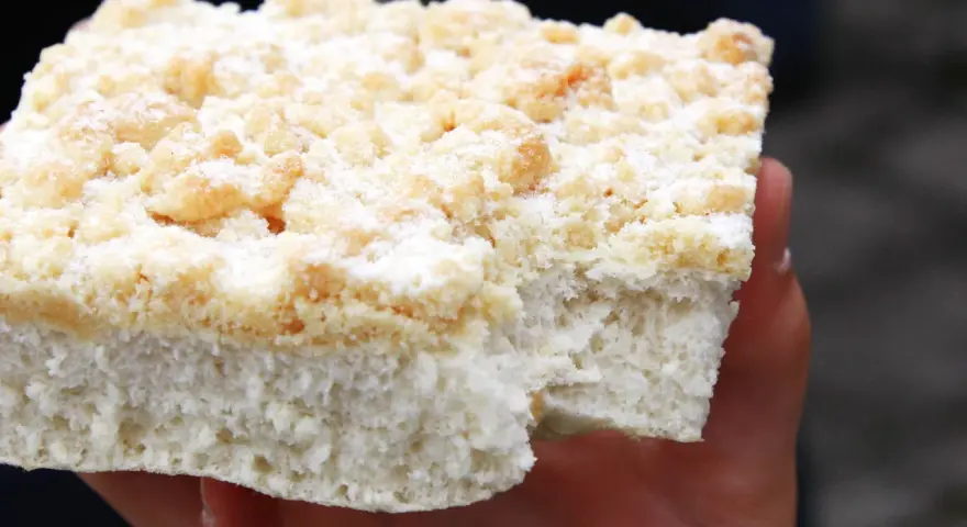 Ein Stück Kuchen mit Streuseln, die ohne Butter zubereitet wurden, liegt auf einer Hand.