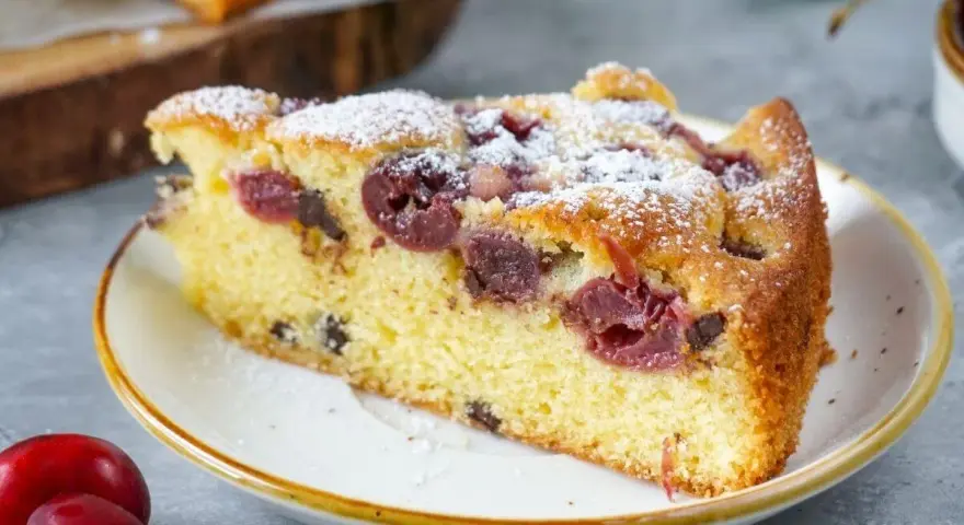 Ein saftiges Stück Kirschkuchen, bestäubt mit Puderzucker. Dieses Kirschkuchen Rezept ist ein Genuss!