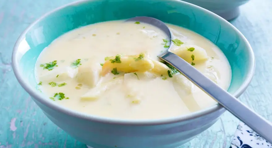 Cremige Spargelsuppe mit Petersilie in einer blauen Schüssel. Perfekt zum Spargelsuppe einfrieren für später.