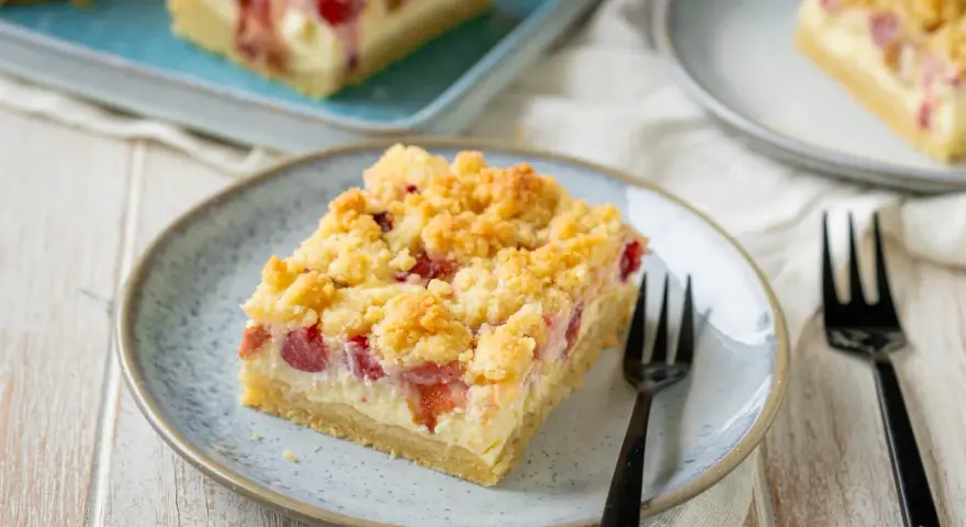 Ein Stück von Omas Rhabarberkuchen mit Quark und Streuseln auf einem Teller, bereit zum Genießen.