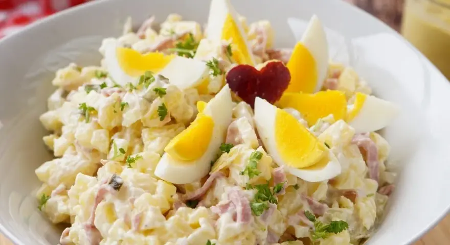 Herzhafter Kartoffelsalat mit Fleischsalat, garniert mit Ei und Petersilie. Ein Klassiker, der immer schmeckt.