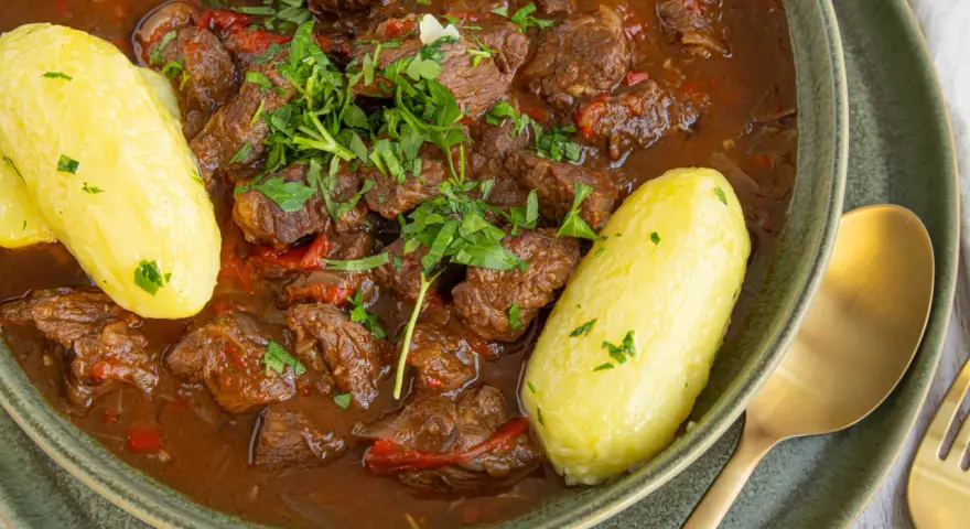 Herzhaftes Gulasch im Schnellkochtopf, serviert mit Salzkartoffeln und frischer Petersilie. Ein Klassiker, der schnell zubereitet ist.