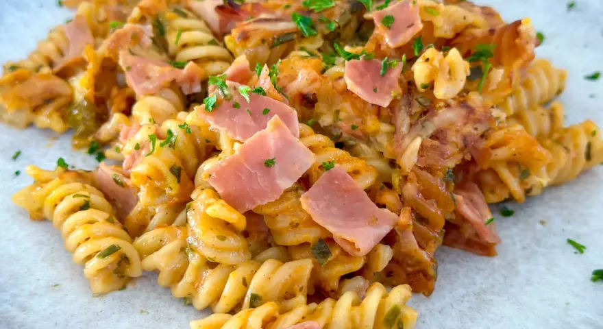 Nudel Schinken Gratin mit Käse überbacken, garniert mit Petersilie. Ein herzhaftes Gericht, das zum Genießen einlädt.