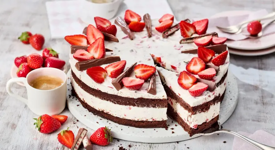 Eine köstliche Yogurette Torte mit frischen Erdbeeren und Schokostückchen, serviert mit einer Tasse Kaffee.